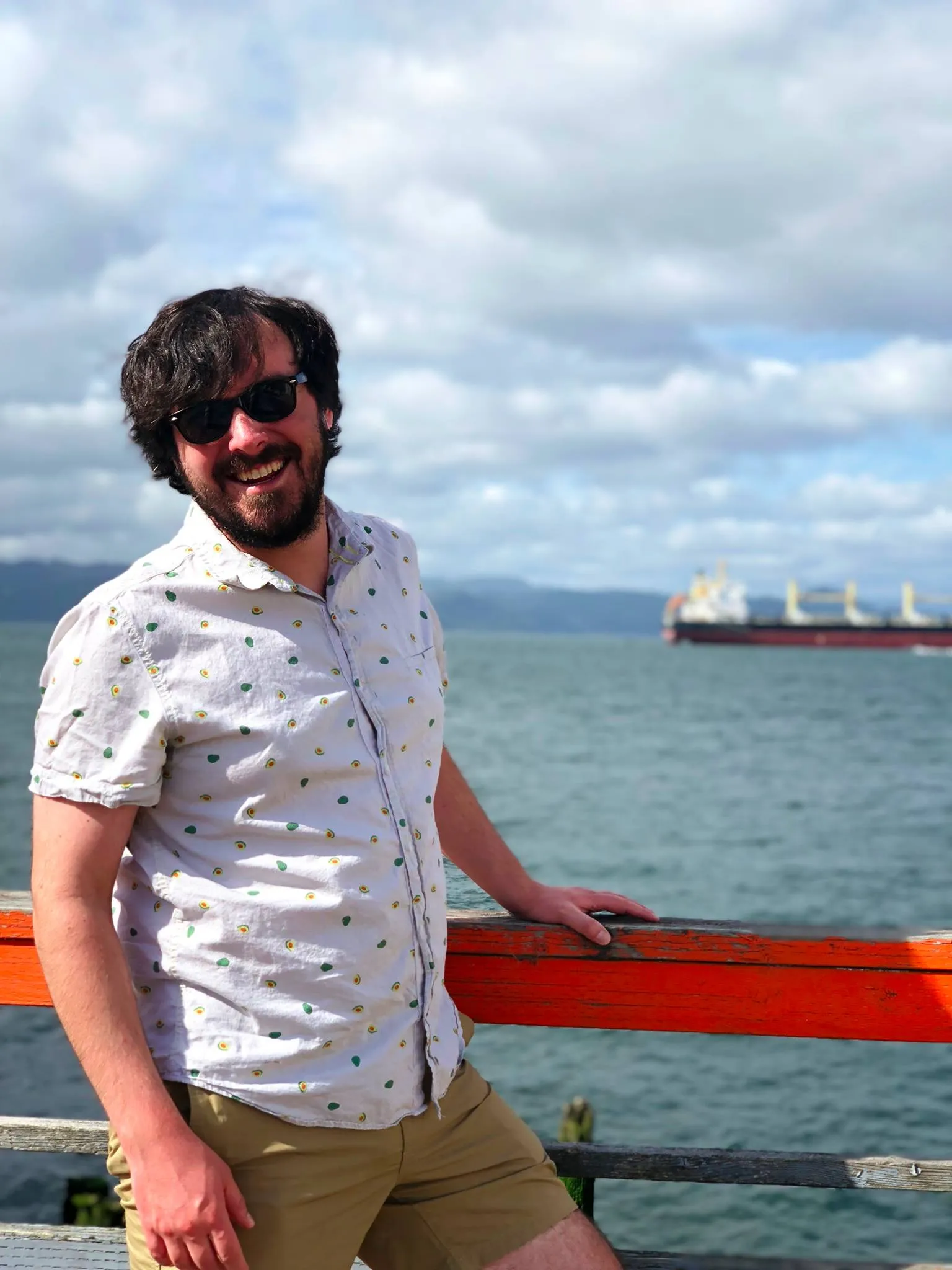 Gerald laughing on a pier, a cargo ship behind him