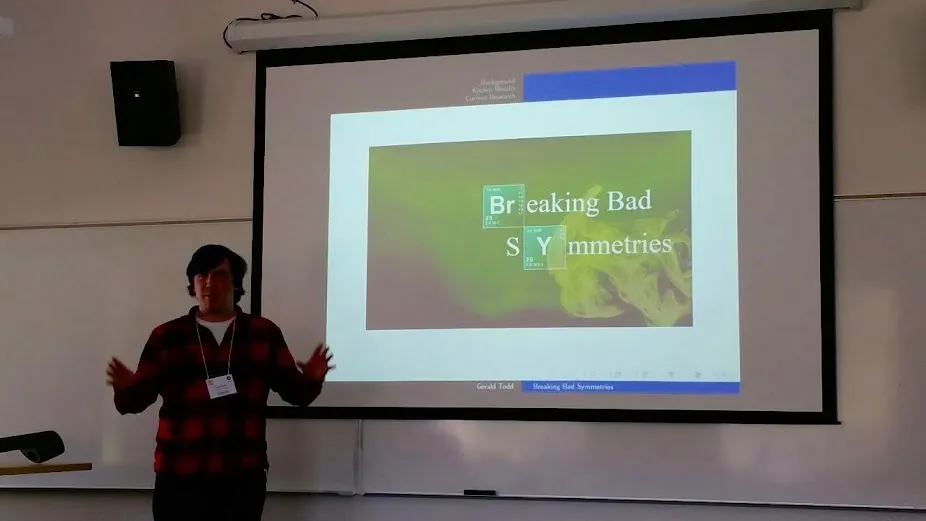 Gerald presenting a talk titled Breaking Bad Symmetries, the title set in Breaking Bad's periodic-table style